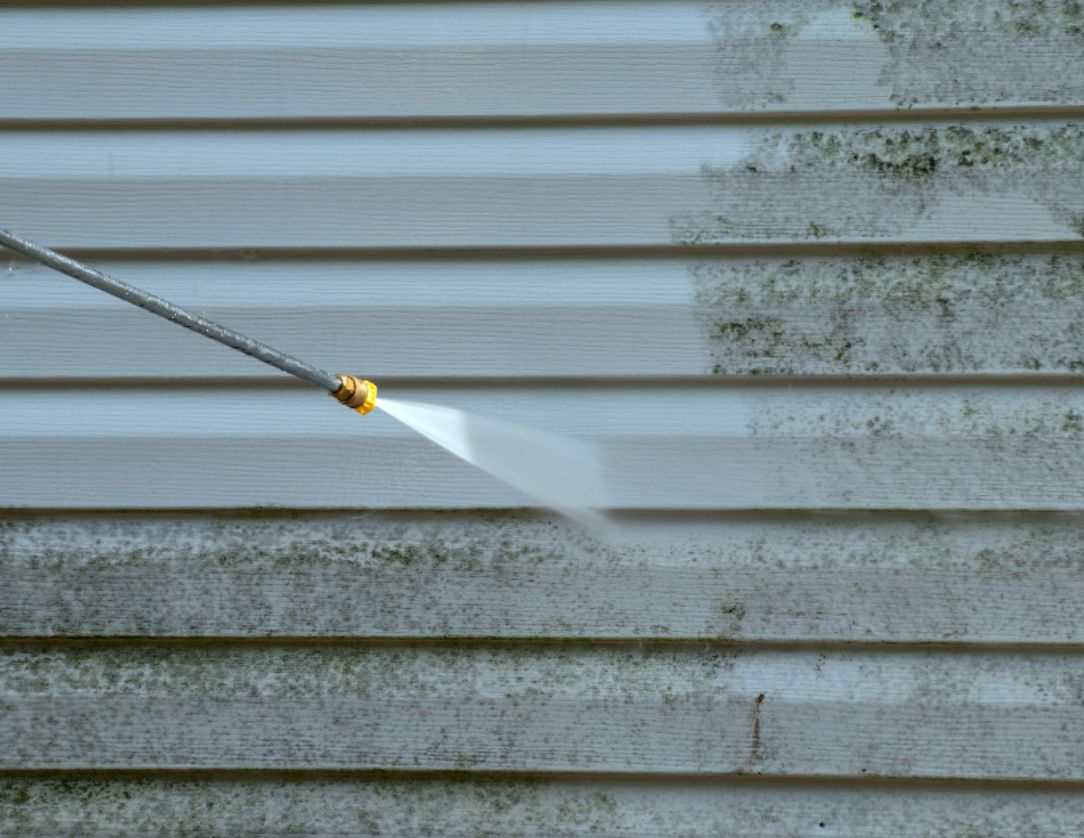 Pressure washing a building's siding to remove mold and grime, showcasing Siding Pressure Washing Services in action with a clean and refreshed appearance.