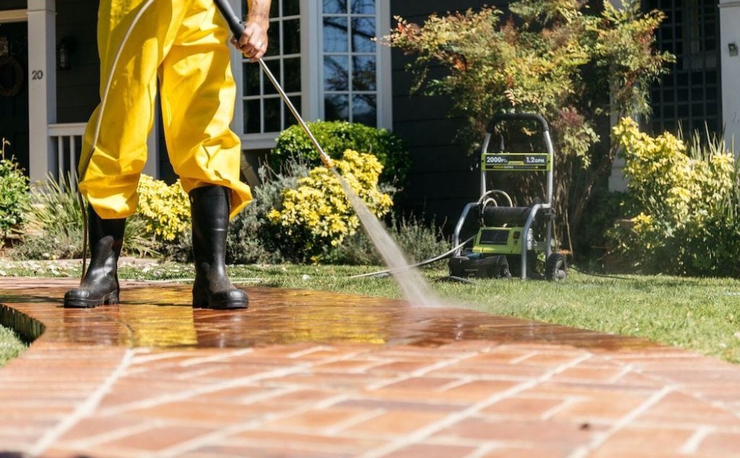 Professional worker pressure washing a brick walkway to remove dirt and buildup, highlighting reliable Commercial Pressure Washing Services for clean, well-maintained exteriors.