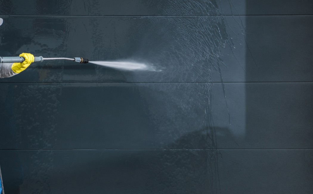 Professional technician pressure washing the exterior wall of a commercial property, removing dirt and grime as part of expert Commercial Building Washing services.