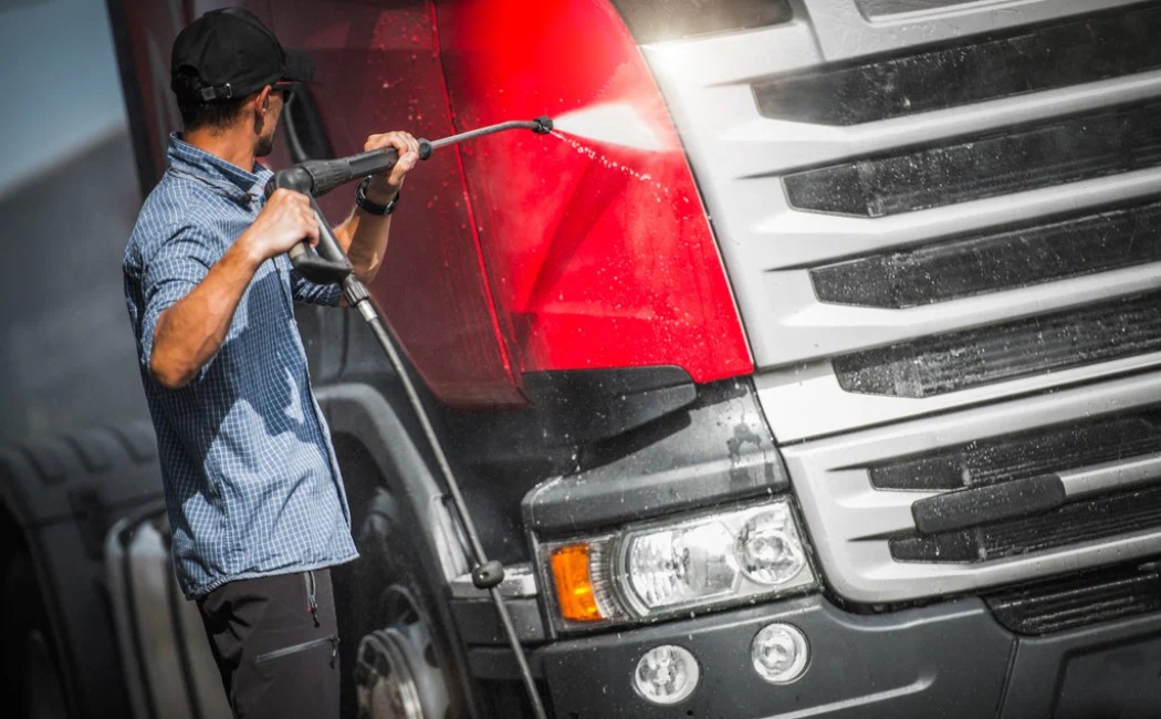 A professional worker performing Industrial Pressure Washing on a large truck, removing dirt and grime using high-pressure water for thorough exterior cleaning.