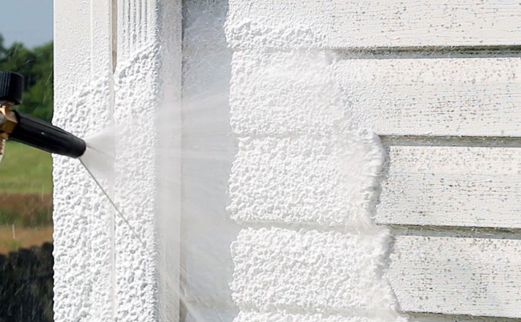 Close-up of professional equipment pressure washing a building exterior wall, removing dirt and buildup with expert Commercial Pressure Washing Services.