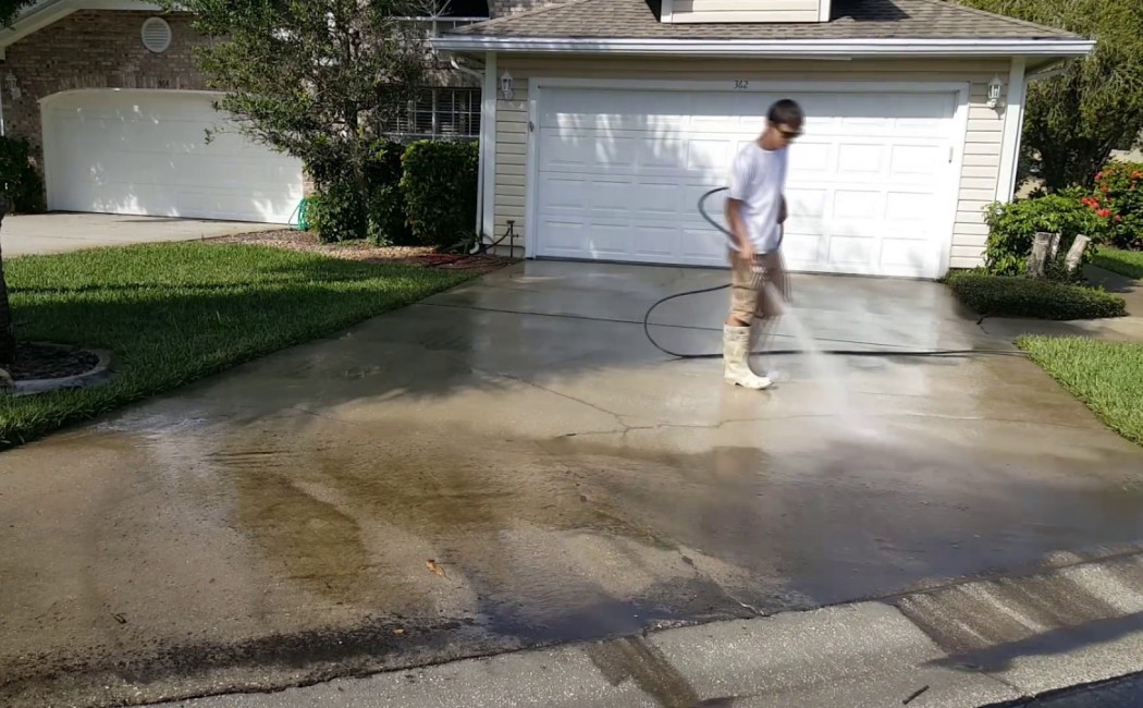 Commercial Pressure Washing Services professional cleaning a residential driveway, removing dirt and stains to restore the concrete surface.