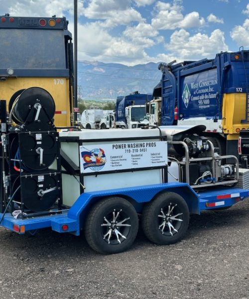A power washing trailer equipped with multiple reels, high-pressure washing equipment, and a service banner for 'Power Washing Pros,' offering commercial, residential, and industrial cleaning services.